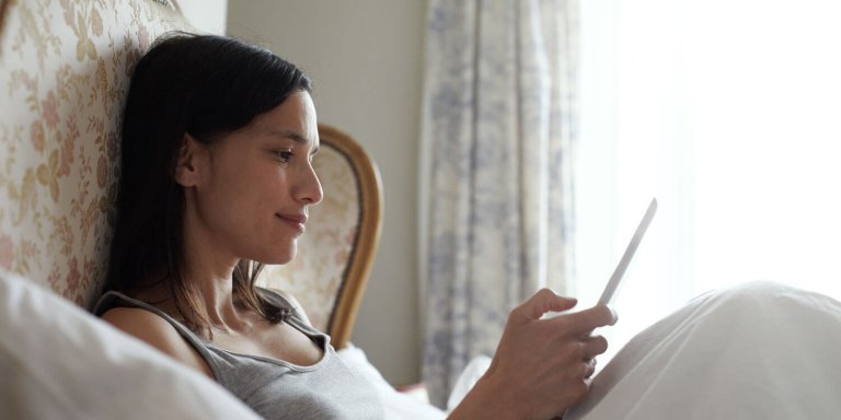 Woman lying down in bed with tablet